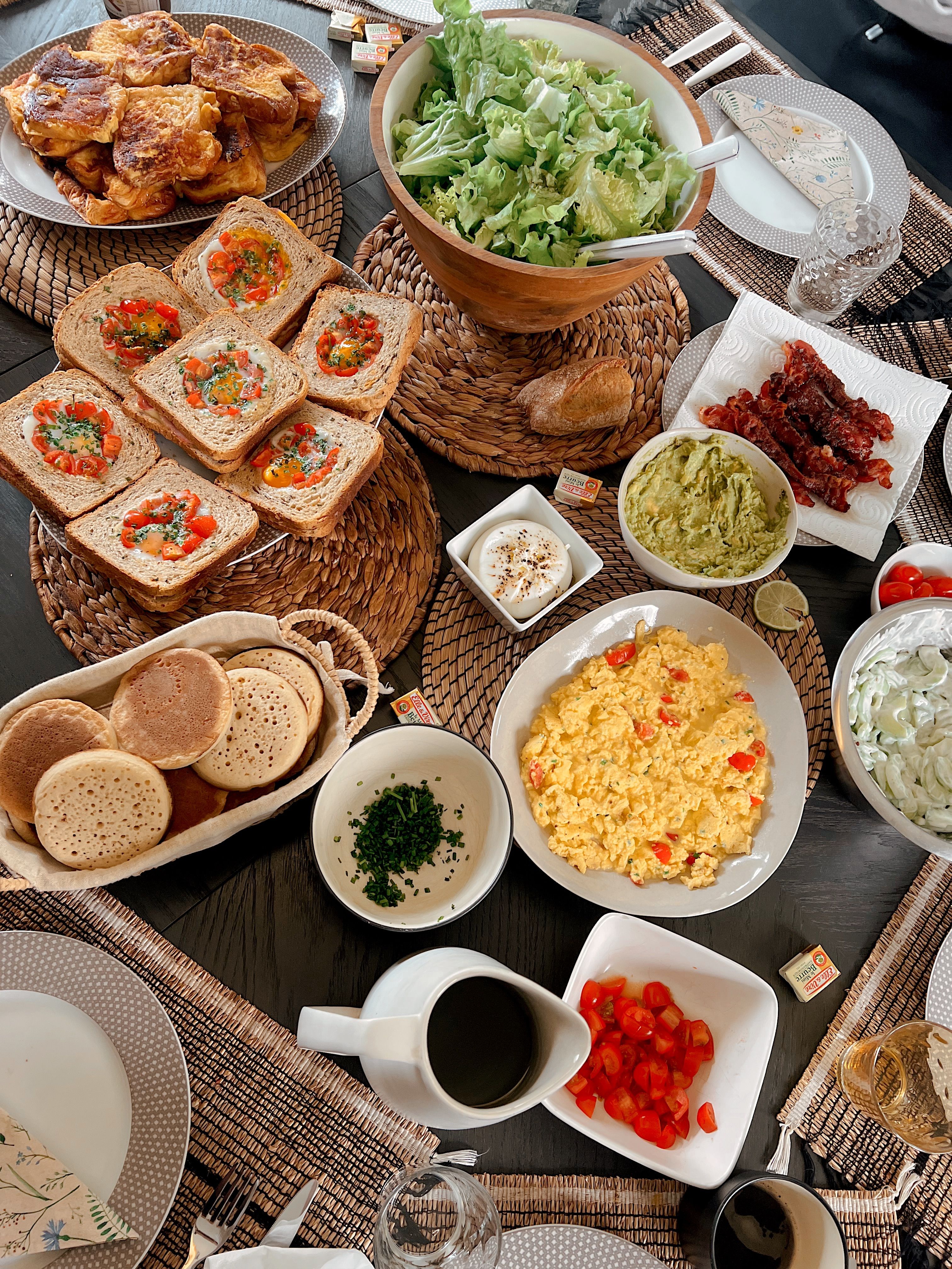 Table garnie pour un brunch : pain perdu, toasts œufs/tomates, salade, bacon, guacamole, œufs brouillés.